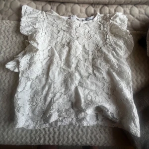 Vit spetsblus med volangärmar - Säljer en söt vit blus i spets med volangdetaljer på ärmarna. 