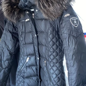 Svart dunjacka Rockandblue med fuskpäls - Snygg svart dunjacka ifrån rockandblue. Använd ca två vintrar då och då men fortfarande fint skick! Säljer då jag ska köpa en annan vinterjacka