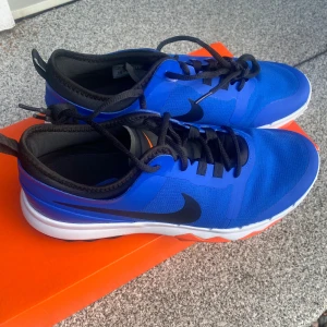 Nike FI Impact 2 blå/svarta golfskor - Nike FI Impact 2 golfskor. Blå med svarta detaljer och svart swoos.Ovandelen är i syntetmaterial och mesh för bra andningsförmåga. Aldrig använda du jag ådrog mig en skada. 