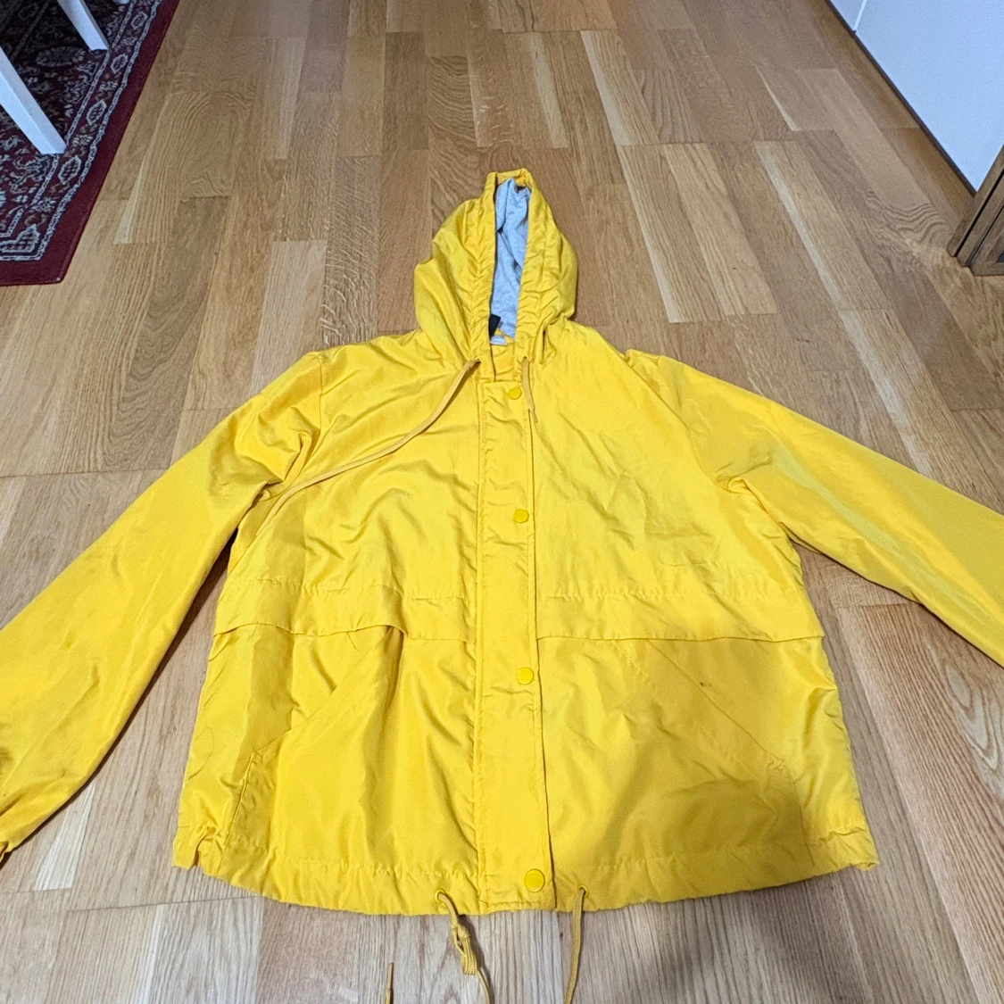 Gul vindjacka med huva och snörning