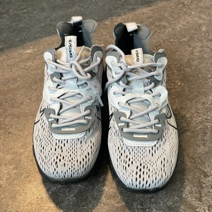 Nike D/MS/X grå sneakers - Nike D/MS/X sneakers i ljusgrå och mörkgrå mesh med svarta detaljer och tydlig Swoosh-logga på sidan. Skorna har snörning, robust svart sula och coola detaljer i syntetmaterial. Perfekta för dig som gillar sportig och modern stil.