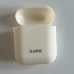 Vit AirPods-fodral från Laut - Säljer ett stilrent vitt AirPods-fodral från Laut. Fodralet är gjort i mjukt syntetmaterial och har en enkel, clean design med Laut-loggan på framsidan. Perfekt för att skydda dina hörlurar och hålla dem fräscha.