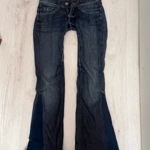 Mörkblå bootcut jeans med kontrastsömmar - Snygga mörkblå jeans med bootcut passform och markerade kontrastsömmar. Jeansen har klassiska fem fickor och coola detaljer på bakfickorna. Perfekta för dig som gillar en retro vibe och vill sticka ut lite extra.