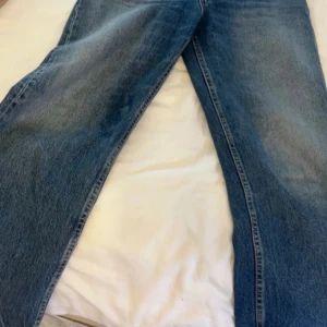Blå bootcut/straight jeans  - Säljer ett par klassiska blå jeans med bootcut passform och snyggt tvättad finish. Jeansen har fem fickor och en rak, något utsvängd benform som ger en retro känsla. Perfekta för dig som gillar en avslappnad men ändå trendig stil.