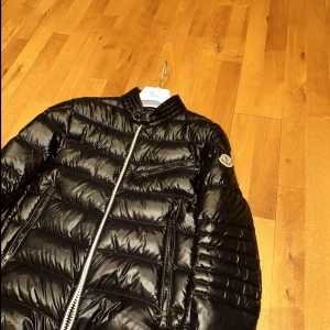 Svart dunjacka från Moncler - Snygg svart dunjacka från Moncler i modellen Bereiat Down jacket. Jackan ser ut som ny och är perfekt nu till hösten. Den köptes in på hayendo och har knappt använts där efter då den var lite fel storlek. 