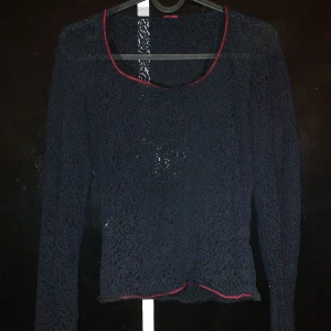 Svart spetsblus med röda detaljer - Så snygg svart blus med röda sömmar o en liten krage i spets, delvis transparent pga mönstret