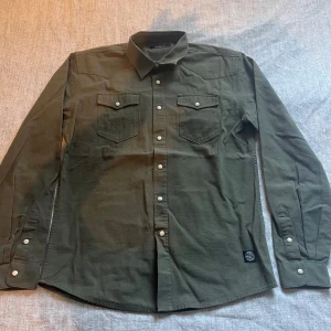 Olivgrön skjorta - Snygg olivgrön skjorta från Cheap Monday, perfekt för dig som gillar enkel men cool stil. Säljer för att den passar inte mig längre. Priset kan diskuteras vid snabb affär!