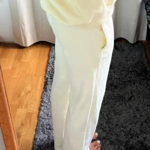 Vita mjukisbyxor med snörning - Säljer ett par vita mjukisbyxor med dragsko i midjan och raka ben. Byxorna har en avslappnad passform och är tillverkade i mjukt bomullsmaterial. Perfekta för chill dagar eller när du vill vara extra bekväm. Säljer matchande hoodie till!! Knappt använda