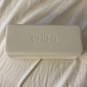 Beige CHIMI solglasögon med fyrkantig form - Snygga solglasögon från CHIMI med transparent beige båge och fyrkantig form. Glasen är mörka och ger en cool kontrast mot den ljusa bågen. Kommer med originalfodral och putsduk. Perfekt accessoar för att lyfta din stil.