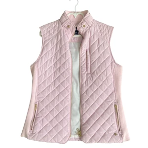 Ljusrosa  väst från  - Supersnygg ljusrosa quiltad väst från Abacus med guldfärgade dragkedjor och knappar. Västen har hög krage, ribbade sidor och flera fickor med dragkedja. Perfekt för lager-på-lager och ger en sportig men chic look.