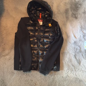 Cardigan Parajumpers - Snygg svart hybrid jacka från Parajumpers i storlek L. Jackan har glansig quiltad framsida och rygg, huva och detaljer i softshell-material. Kvitto finns, nypris 6000kr✅😁 kom om vid några som helst funderingar inga skambud!