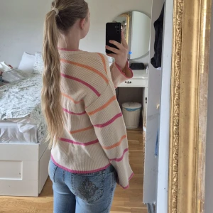 Randig beige stickad tröja - Superfin ribbstickad tröja från Samsa Collection i beige med rosa och orange ränder. Tröjan har rund halsringning och långa ärmar. Ej knottrig eller så. Super skön och mjuk! Säljer då den inte används, använd fåtal gånger. Hör gärna av dig vid frågor och funderingar💕