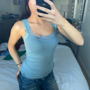 Ljusblå ribbad linnetopp med spets - Säljer en ljusblå ribbad linnetopp med breda axelband och snygga spetsdetaljer.