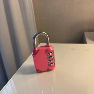 Rosa kodlås  - Säljer ett rosa kodlås med fyrsiffrig kombination, perfekt att använda till din väska eller ryggsäck. Låset är i metall och plast, har en snygg och kompakt design och är lätt att ställa in med egna koder. Smidigt att ta med och ger extra säkerhet.