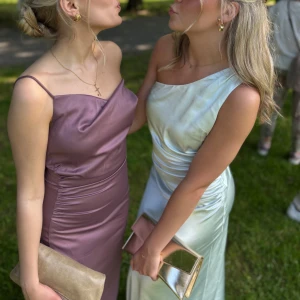 Ljusblå balklänning  - Säljer min jättefina balklänning (endast använd en gång) Klänningen är i satinmaterial med oneshoulder och snygga draperingar längs sidan. Klänningen har en fin passform och ser väldigt lyxig ut! Pefekt för bal eller som bröllopsgäst klänning. Nypris 1800kr