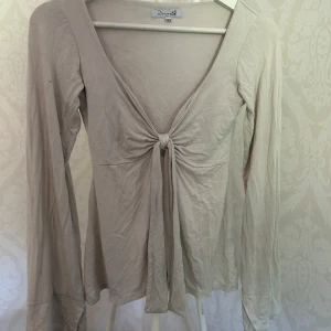 Vit långärmad topp med knyt - Supersnygg vit långärmad topp från Design by Si. Toppen har djup v-ringning och en cool knytdetalj framtill som ger en trendig look. Perfekt att styla med jeans eller kjol för en chill vibe.