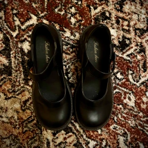 Svarta Mary Jane ballerinaskor med klack - Chunky Mary Jane ballerinaskor i svart skinnimitation med bred rem och spänne över foten. Skorna har rund tå, kraftig plattformssula och låg klack för en edgy vibe. Endast använda en gång och skulle inte rekommendera att gå långa sträckor i! Fick skavsår av en dag på Stockholms gator😬Men är så kär i dem😍
