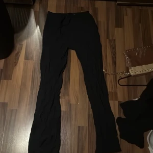 Svarta mjukisbyxor med snörning - Svarta mjukisbyxor med dragsko i midjan. Byxorna har en rak passform och är tillverkade i ett mjukt material som känns skönt mot huden. Perfekta för chill dagar eller när du vill vara bekväm men ändå se stilren ut.