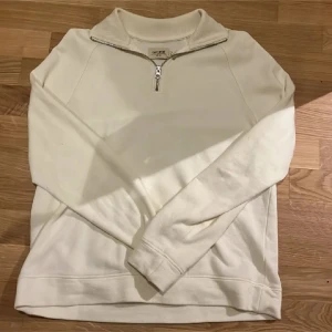 Vit half zip sweatshirt från East West - Snygg vit sweatshirt från East West med half zip-dragkedja och hög krage. Tröjan är långärmad och har en clean, enkel design som passar perfekt till jeans eller mjukisbyxor. Pris kan diskuteras 