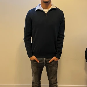 Mörkblå tröja med half zip - Snygg mörkblå långärmad tröja med halv dragkedja i halsen och ljusgrå insida på kragen. Tröjan har en klassisk passform och är gjord i mjukt material som känns skönt mot huden. Perfekt för dig som gillar stilrena och enkla plagg. Nypris:699Kr. Mitt pris:199Kr✅