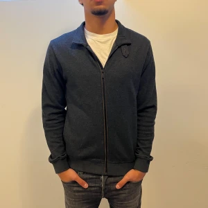 Mörkgrå cardigan från Massimo Dutti - Snygg mörkgrå cardigan från Massimo Dutti med hel dragkedja och klassisk krage. Jackan är i mjukt material och har en clean look utan mönster. Perfekt för lager-på-lager och funkar till många olika stilar. Sjukt fin kvalite wool blend. Nypris: 1699Kr Mitt pris:499Kr ✅