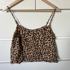 Leopardmönstrad linnetopp från Divided - Säljer en beige linnetopp från Divided med leopardmönster och tunna justerbara axelband. Toppen har en loose passform och är perfekt för dig som gillar att sticka ut med djurmönster. Materialet är mjukt och lätt polyester som känns skönt mot huden.