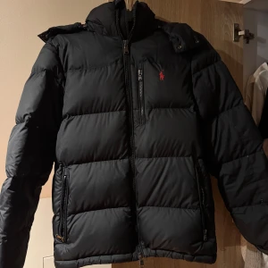 Svart pufferjacka Polo Ralph Lauren - Svart jacka från Polo Ralph Lauren med vattenavvisande material. Jackan är endast använd max 5 gånger så i princip i nyskick. Storlek s, jackan köptes för 4500, pris är diskuterbart vid snabbt affär😊