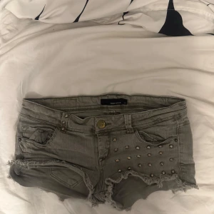  jeansshorts med nitar Tally Weijl - Snygga jeansshorts från Tally Weijl med låg midja och fransade kanter. Shortsen har coola nitar på framsidan, klassiska fickor och knappstängning. Perfekt för dig som gillar edgy och trendig stil.