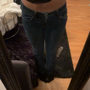 Mörkblå bootcut jeans  - Säljer ett par mörkblåa jeans me bootcut och snygga detaljer på bakfickan. Jeansen har låg midja och är i ett mjukt denimtyg med lite stretch. Perfekta för dig som gillar en tidlös look och vill ha ett par jeans som sitter skönt hela dagen.