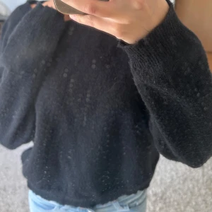 Svart stickad tröja med loose fit - Mysig svart stickad tröja med rund hals och långa ärmar. Modellen är loose fit och har ribbade muddar vid ärmslut och nederkant. Perfekt att slänga på sig när det är kyligt ute. Passar dig som gillar en enkel och chill stil. 