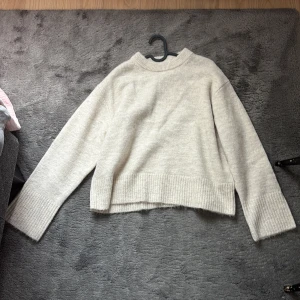 Beige stickad tröja - Mysig beige stickad tröja med breda ribbade muddar vid ärmslut och nederkant. Helt oanvänd men säljer pga att jag inte har fått användning