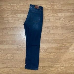 Mörkblå high waist jeans - Snygga mörkblå jeans med hög midja och klassisk femficksdesign. Jeansen har raka ben och subtila slitningar framtill för en cool look. Tillverkade i stretchig denim som sitter skönt hela dagen. Perfekta till sneakers eller boots.