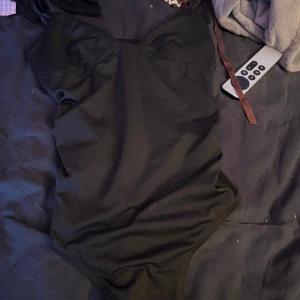 Svart body  - Snygg svart body med  formade kupor. Klassisk modell med smala axelband och stilren look, perfekt för stranden eller poolen. Materialet är stretchigt och följsamt för en bekväm passform.