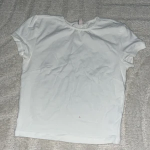 Vit basic t-shirt i bomull - Enkel och stilren vit t-shirt med rund hals och korta ärmar. Perfekt att matcha med jeans eller shorts för en clean look. Gjord i mjuk bomull som känns skön mot huden.