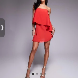 Röd axelbandslös kortklänning - Snygg röd axelbandslös kortklänning med volangdetalj. Såå snygg men tyvärr lite kort på mig (är 172), jättefin o passar till många tillfällen. Aldrig använd, ny pris 700