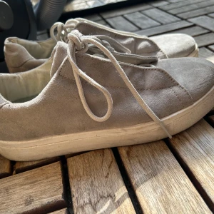 Grå mockasneakers från Bianco - Snygga grå sneakers från Bianco i mjuk mocka med klassisk rund tå och vita snören. Skorna har en platt sula och stilren design som passar perfekt till jeans eller shorts. Enkla att matcha och riktigt bekväma för vardagen. Made in Italy 