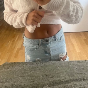 Ljusblåa ripped jeansskjol - Snygg ljusblå jeanskjol från Ivy med slitna detaljer och råa kanter. Klassisk femficksmodell, dragkedja och knapp framtill. Perfekta för sommaren och ger en cool, avslappnad vibe.