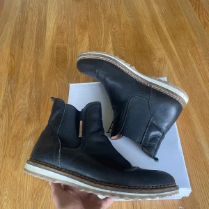 Björn Borg Chelsea boots – Svarta läderskor herr - 🧼 Skick: Mycket bra skick – använda få gånger, inga sprickor eller tydliga märken. 👞 Storlek: EU 43 🎨 Färg: Svart 📍 Modell: Chelsea boots med elastiska paneler och rejäl vit sula 🪵 Material: Äkta läder och slitstark gummisula 🍂 Perfekt för: Höst, vinter och vår – stilrena och bekväma 📦 Frakt: Skickas snabbt och välpaketerat. Originalkartong kan ingå om önskat 💬 Skriv gärna vid frågor eller om du vill ha fler bilder!