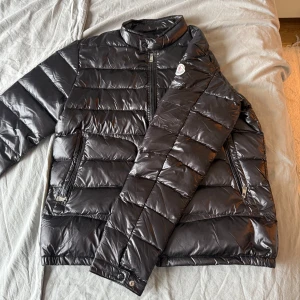 Svart Moncler pufferjacka - Säljer nu denna riktigt snygga moncler jacka då den inte passade mig. Perfekt för lite kallare kvällar. storlek 4 så passar från 180-190 beroende på kroppsform.