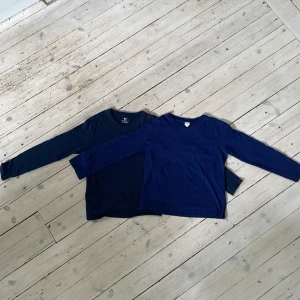 Två marinblå långärmade tröjor H&M - Säljer två basic långärmade tröjor från H&M i marinblått. Båda har rund halsringning och är gjorda i mjuk ekologisk bomull. Perfekta att matcha med jeans eller under en hoodie. Enkla ,användbara och passar till allt. Den ena tröjan har två ytterst små hål på baksidan om man kollar nogra, men ingenting som påverkar själva plagget.