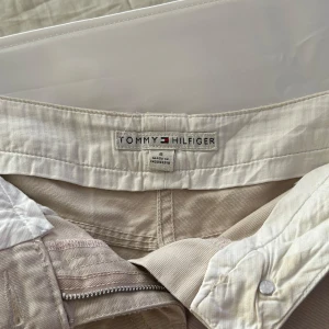 Tommy Hilfiger shorts - Tommy Hilfiger shorts, beiga med äkta bakfickor som går att stänga. Supercoola men kommer ej till använding.