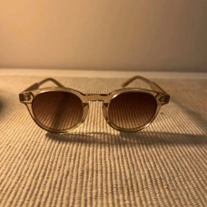 Beige runda solglasögon från Chimi - Snygga solglasögon från Chimi med transparent beige båge och runda bruna glas. Klassisk och trendig modell som passar perfekt till sommaren. Kommer med originalfodral och tygpåse. Perfekta accessoaren för en cool look.