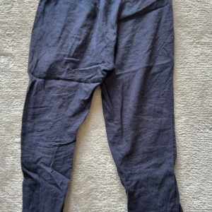 Mörkblå linnebyxor från H&M - Snygga mörkblå linnebyxor från H&M i regular fit. Byxorna har resår i midjan för extra komfort och är tillverkade i ett lätt och luftigt linnematerial. Perfekta för en avslappnad och stilren look.