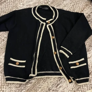 Svart kofta med vita detaljer  - Svart kofta från DAZY i storlek S med vita kanter och guldiga knappar. 