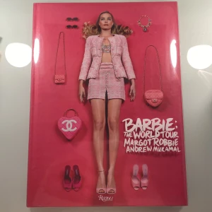Barbie: The World Tour - Bok fylld med ikoniska Barbie-looks ft. Margot Robbie för den senaste Barbie filmen. Perfekt för dig som älskar mode, popkultur, kända märken och vill dyka in i Barbies värld av kreativitet och stil, kan också användas som dekoration. Boken köptes från Adlibris för 430kr och har knappt använts. 