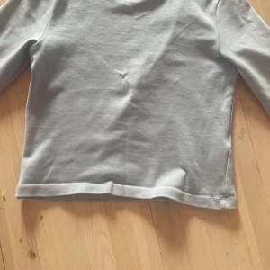 Ljusgrå långärmad tröja Gina Tricot - Enkel och stilren ljusgrå långärmad tröja från Gina Tricot. Tröjan har rund halsringning och är gjord i mjuk bomull, perfekt för en clean och chill look. Passar dig som gillar basic plagg med snygg passform.