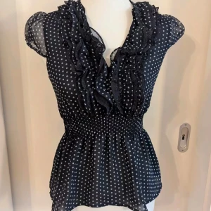prickig blus  - supersöt marinblå blus från h&m med vita prickar, volangdetaljer längs v-ringningen och smockad midja💕