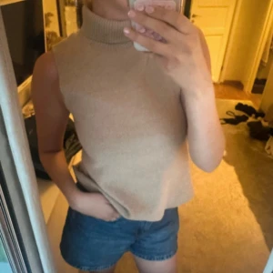 Beige stickad polotopp ärmlös - Säljer en beige stickad polotopp med hög krage och ärmlös design. Toppen har en mjuk och lite loose passform, perfekt att styla med jeans eller kjol. Enkel och stilren look som funkar året runt. Jag skickar paketet idag om du köper den idag! 💞
