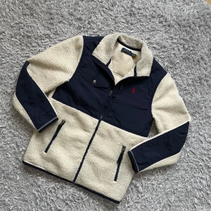 Ralph Lauren Fleecejacka  - Säljer denna mycket fina och trendiga Raffe fleecen som är perfekt till våren! | Den är i mycket fint skick, har något litet smuts som inte är speciellt synlig och kan säkert gå bort om tvättar noga! | Storlek XS men skulle säga att den sitter lite stort i storleken, är själv 165 och sitter för stort på mig. | Ställ gärna frågor innan du köper!
