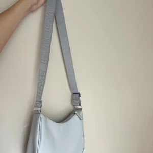 Ljusgrå axelväska från h&m - Säljer en stilren ljusgrå axelväska från h&m med bred, justerbar axelrem. Väskan har en minimalistisk design, dragkedja upptill. Använd en knappt antal gånger bara 🤍😌